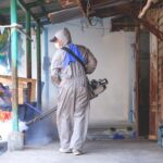 Healthcare worker using fogging machine spraying chemical to removal mosquitoes in slum area
